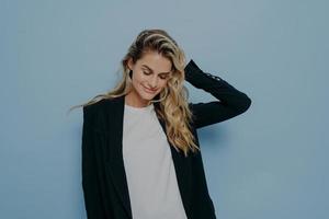 Beautiful smiling female with blonde dyed hair feeling happy while posing in studio photo