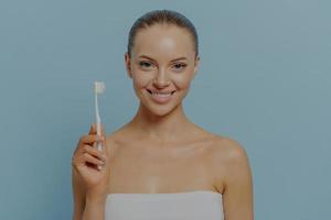 higiene oral. mujer joven feliz cepillando los dientes después de la ducha, mujer sonriente sosteniendo cepillo de dientes foto