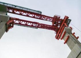 grúa roja para la construcción del puente del tren. foto