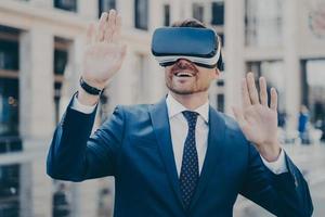 Office worker in formal suit exploring virtual world with VR glasses while relaxing outdoors photo