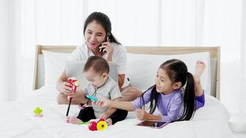 madre asiática con una hija pequeña y un bebé usando un estilo de vida hogareño portátil