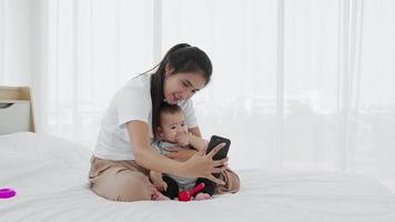 A single mother shows her baby girl to take photos with a smartphone video