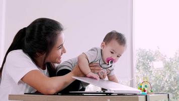 madre freelance lavora a casa. maternità moderna, piccola bambina. educazione online dei bambini video