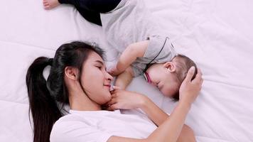 joven madre y su bebé durmiendo juntos en la cama. familia feliz video