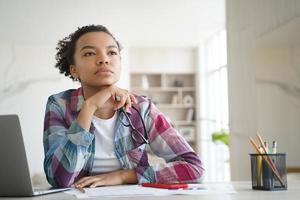 la adolescente afro está aburrida en la lección en línea. estudio remoto en la escuela secundaria o la universidad en casa. foto