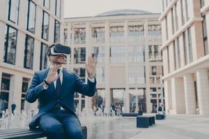 Impressed young businessman or office worker testing virtual reality goggles, using VR headset photo