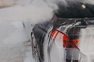 Professional car wash with high pressure washer and cleansing foam outdoors photo