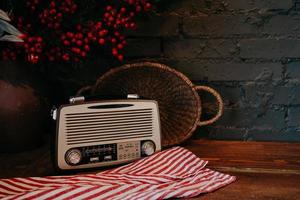 radio retro sobre mesa de madera con cesta de mimbre y decoración floral. estilo vintage. antiguo receptor de radio de difusión sobre fondo rústico. foto