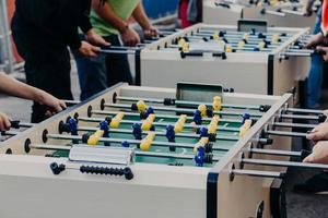 People, entertainment and recreation concept. Unrecognizable friends have fun together, play table football or kicker, rest in pub outdoor photo