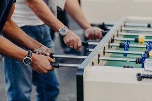 vista recortada de las manos masculinas jugar al futbolín, disfrutar de la recreación o el tiempo libre durante las vacaciones, pasar el tiempo libre en el bar. concepto de competencia foto