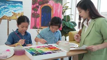 madre enseñando a su hija a pintar color agua en clase de arte en casa video