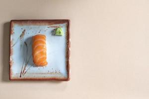 Japanese food salmon sushi in plate has chopsticks on brown wood background. photo