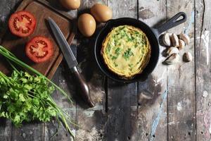 Egg breakfast food omelet has vegetable in pan on wood table. photo