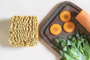 Asian food instant noodle has vegetable ingredient on pink wood table. photo