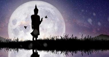 Silhouette of Buddha mediating with Full moon at night. Buddhist holiday Concept. photo