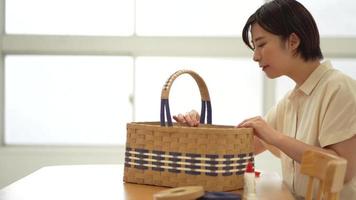 A woman making a basket with a craft band video