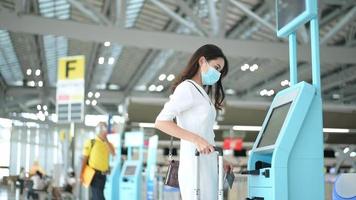 uma mulher viajante está usando máscara protetora no aeroporto internacional, viaja sob pandemia covid-19, viagens de segurança, protocolo de distanciamento social, novo conceito de viagem normal. video