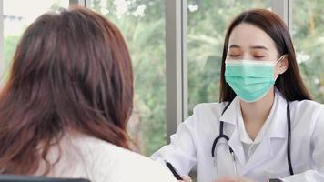 A female doctor or nurse with a surgical mask is talking or interview a middle-aged female patient, ideas for healthcare concepts.