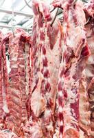 la costilla de cerdo cruda está colgada en la tienda de carne de cerdo. foto