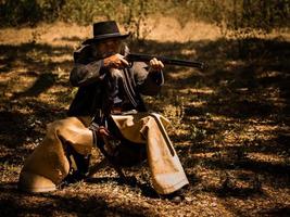 A senior cowboy sat with a gun to guard the safety of the camp in the western area