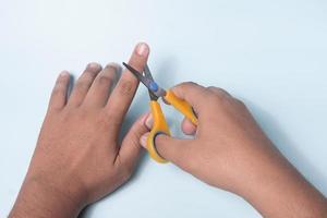 la mano de un hombre está tratando de cortar un dedo con unas tijeras foto