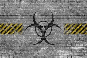 Faded biohazard sign with yellow black lines on a brick wall photo