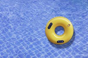 anillo amarillo flotando en el agua de una ola azul en la piscina al aire libre. vacaciones de verano foto