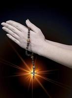 praying hands with a rosary on a black background photo