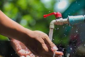 concepto de agua en la vida cotidiana. manos sosteniendo el agua que fluye del grifo. agua salpicando del grifo foto