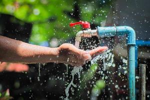 Water concept in everyday life. Hands supporting the water flowing from the faucet. water splashing from the tap photo