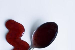 the drops of homemade sauce and a spoon on a white background photo