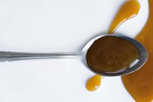 the drops of homemade sauce and a spoon on a white background photo