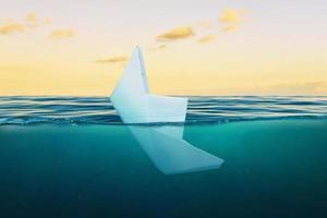 un barco de papel hundiéndose en el mar. el concepto de fracaso en los negocios y la vida privada foto