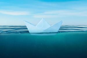 Paper boat on the sea surface. View under the sea. The concept of courage and bravery in life and the risk of making bad decisions that can sink a ship photo