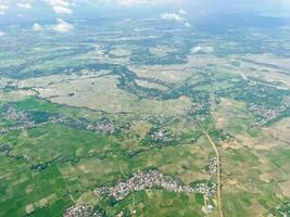 el paisaje aéreo muestra una vista verde de la ciudad. calles, campos de arroz y casas de pueblo. foto