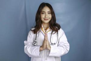 A young Asian female doctor is smiling and giving greeting gesture photo