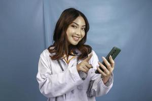 Young Asian woman doctor is pointing and showing green screen or copy space on her smartphone photo