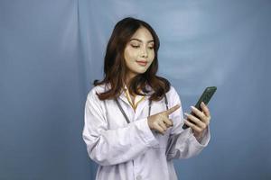 Young Asian woman doctor is pointing and showing green screen or copy space on her smartphone photo