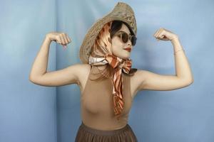 joven asiática fuerte mostrando sus bíceps aislada por un fondo azul foto