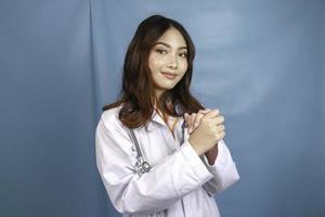 A portrait of a young Asian female doctor is praying to God photo