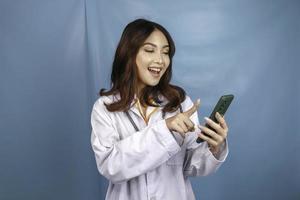 Young Asian woman doctor is pointing and showing green screen or copy space on her smartphone photo