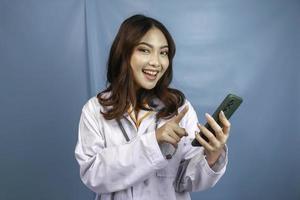 Young Asian woman doctor is pointing and showing green screen or copy space on her smartphone photo