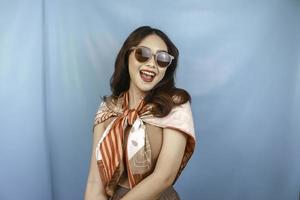 Traveling concept of a young Asian happy woman isolated by a blue background. photo