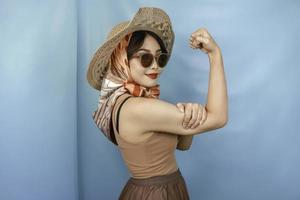 Young Asian strong woman showing her biceps isolated by a blue background photo