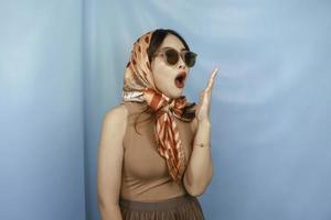 Retro concept of a young Asian sleepy woman is yawning, isolated by a blue background photo