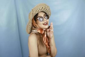 Traveling concept of a young Asian happy woman isolated by a blue background. photo