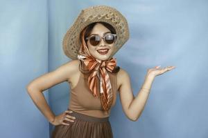 Young Asian happy woman isolated by a blue background pointing copy space on the side. photo