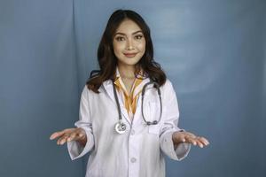 Young doctor woman presenting an idea while looking smiling on isolated blue background photo