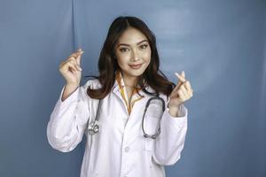 un retrato de una joven doctora asiática muestra el dedo del corazón o un gesto de amor foto