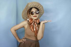 Young Asian happy woman isolated by a blue background pointing copy space on the side. photo